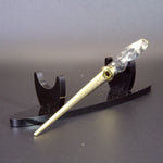 Letter opener with metal fitting on a black stand against a gray background