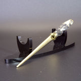 Letter opener with metal fitting on a black stand against a gray background