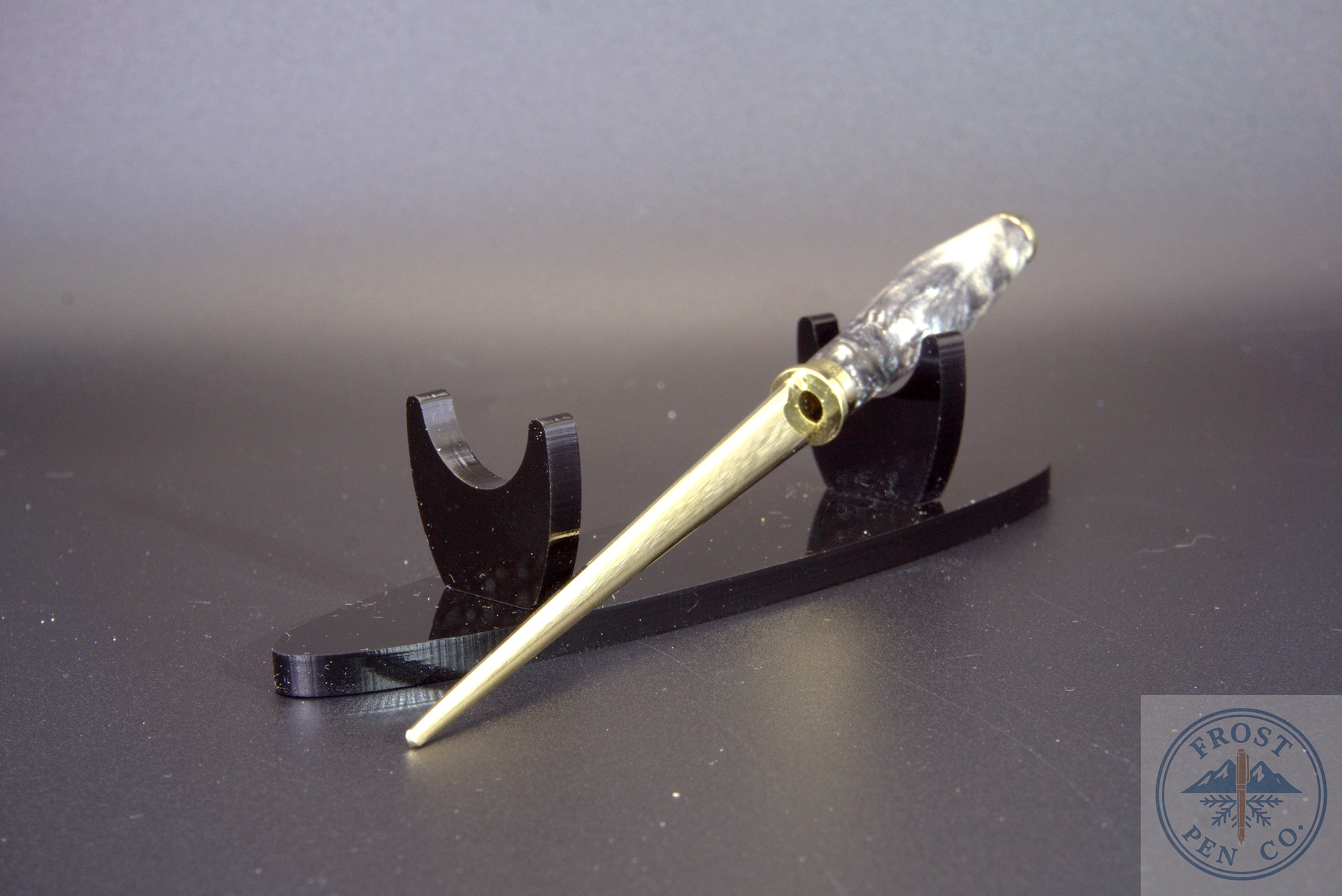 Letter opener with metal fitting on a black stand against a gray background