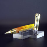 Pen with gold accents on a clear stand against a dark background