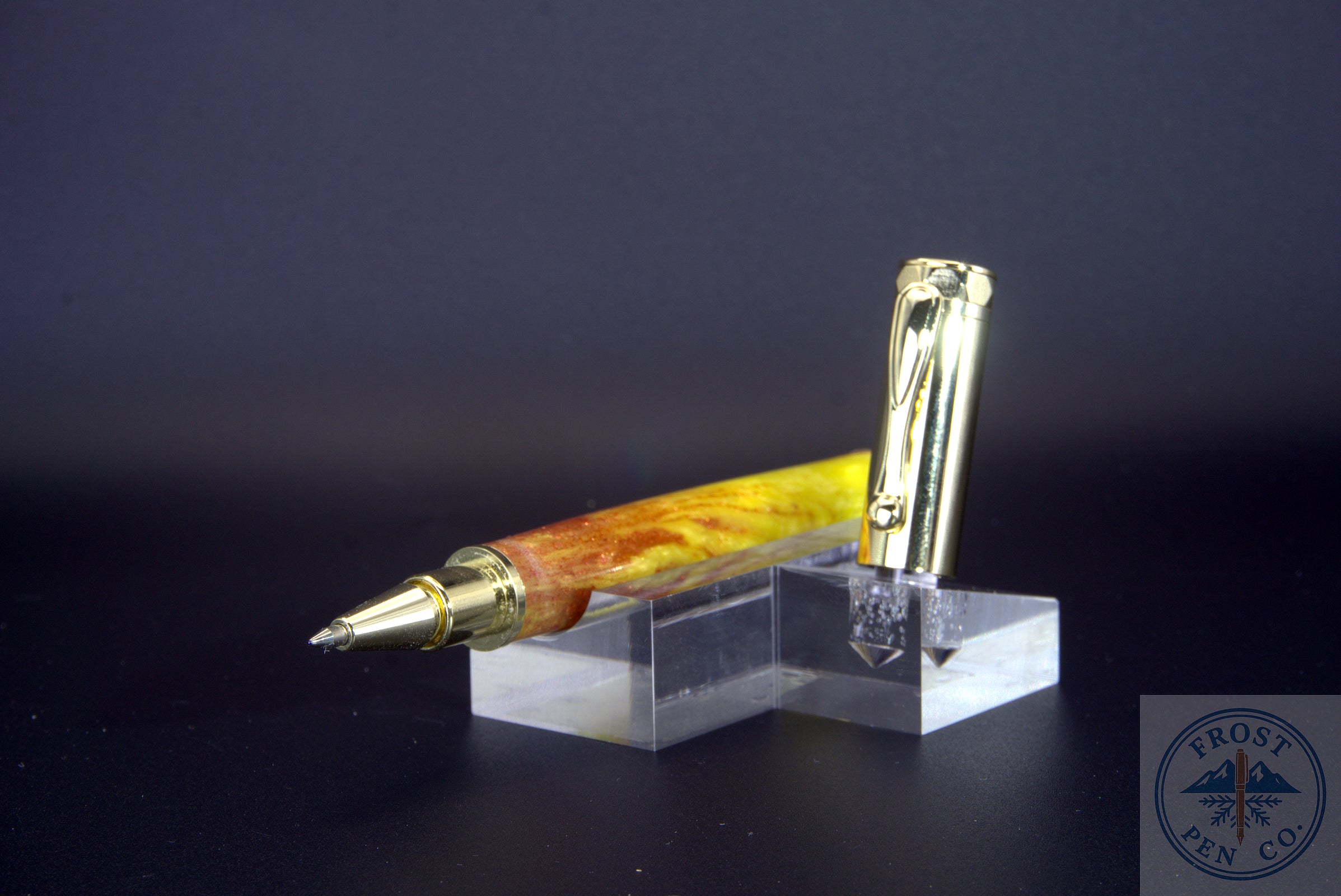 Pen with gold accents on a clear stand against a dark background