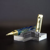 Fountain pen with gold accents on a clear stand against a dark background