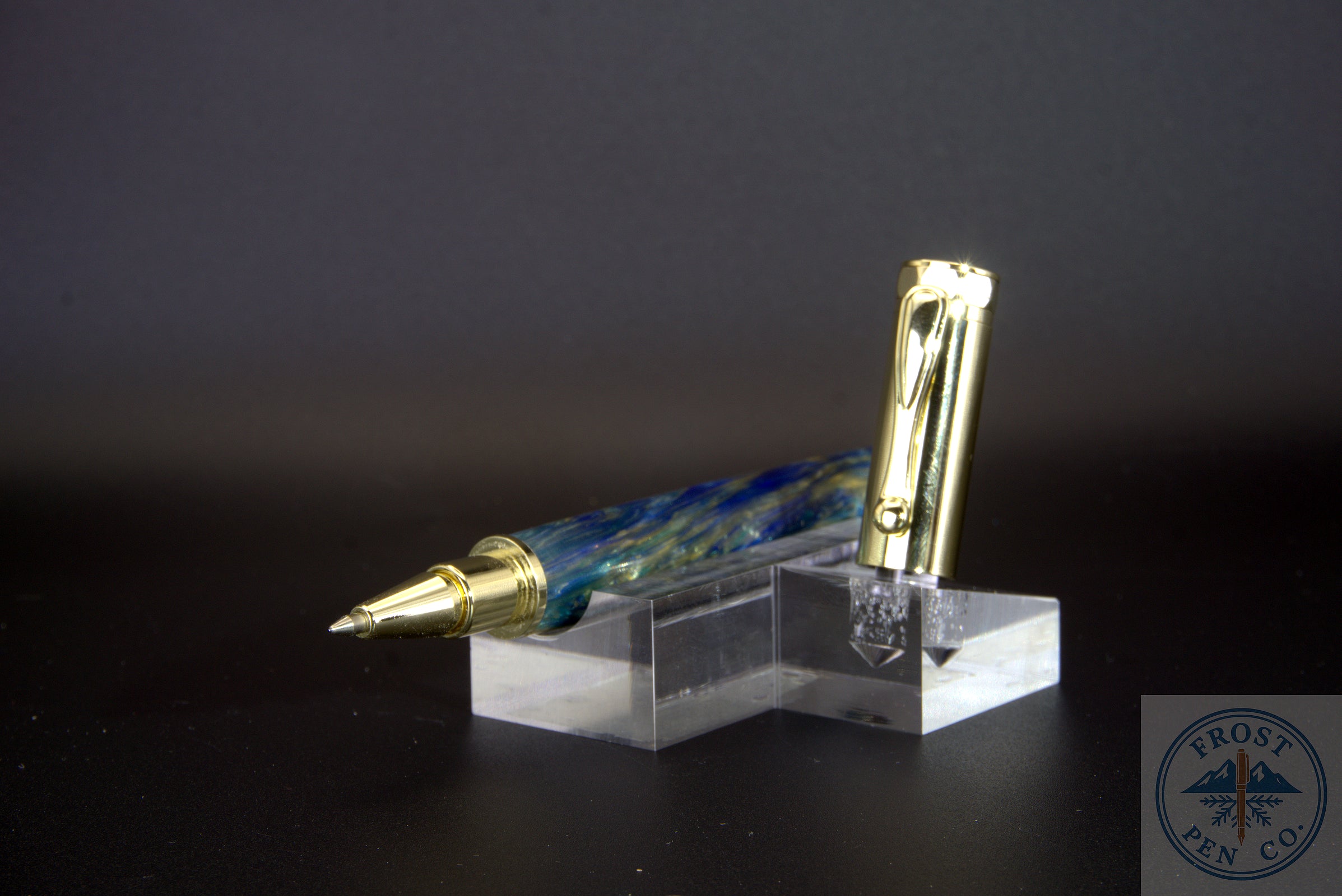 Fountain pen with gold accents on a clear stand against a dark background