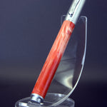 Pen with red handle and silver accents on a clear stand against a dark background