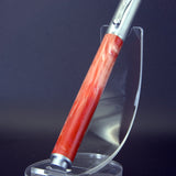 Pen with red handle and silver accents on a clear stand against a dark background