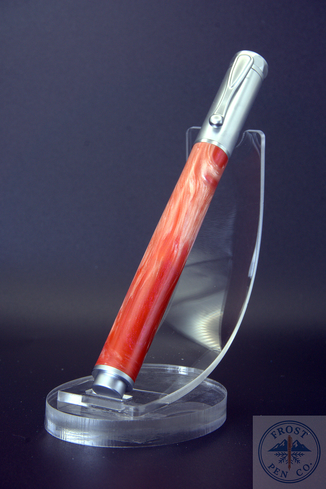 Pen with red handle and silver accents on a clear stand against a dark background