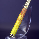 Fountain pen with yellow and brown body on a clear stand against a dark background