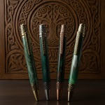 Four green pens with gold accents on a wooden surface with intricate carvings.